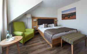 インゲルハイム・アム・ラインにあるフェッツァース ラントホテルのベッドと緑の椅子が備わるホテルルームです。