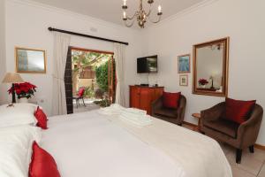a bedroom with a large white bed and two chairs at A Tuscan Villa Guest House in Fish Hoek