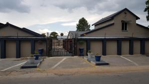 a building with a gate in a parking lot at Rustique Paris Guest House in Parys
