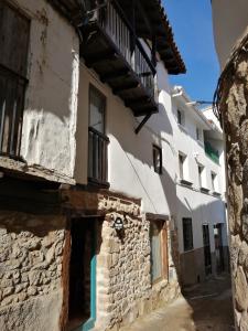 un callejón en un antiguo edificio de piedra con balcón en VEN LUNA, VEN Casa-SPA Astroturismo rural TR-CC-00361 en Casas del Castañar