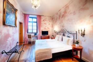 a bedroom with a large white bed and a desk at Hotel Schloss Lehen in Bad Friedrichshall