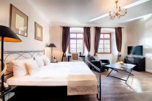 a bedroom with a large white bed and a living room at Welcome Hotel Schloss Lehen in Bad Friedrichshall