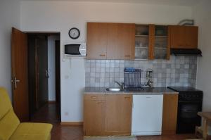 eine Küche mit Holzschränken und einem weißen Kühlschrank in der Unterkunft Poseidon Apartments in Plomin