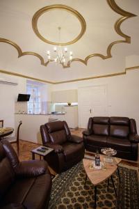 a living room with leather furniture and a chandelier at Little Vienna Gold Apartment in Varaždin