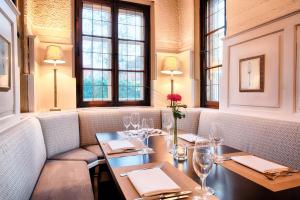 um restaurante com mesa, cadeiras e janelas em Welcome Hotel Schloss Lehen em Bad Friedrichshall