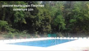 a large swimming pool with trees in the background at Wisteria Cottage in Fleurines