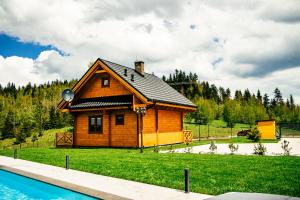 a log cabin with a pool in front of it at Cztery Pliszki in Zawoja