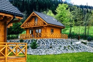 a log cabin with a stone yard in front of a house at Cztery Pliszki in Zawoja