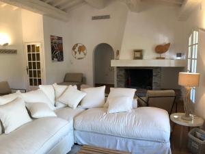 a living room with white couches and a fireplace at Maison sous les Pins in Cavalaire-sur-Mer