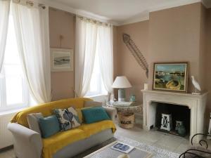 a living room with a yellow couch and a fireplace at Villa Fleur de Sel in Fouras