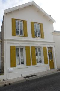 a white house with yellow shutters on it at Villa Fleur de Sel in Fouras