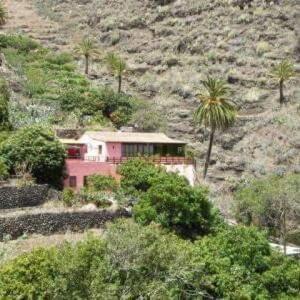 una casa rosa en una colina con palmeras en Casa Rural Rincón del Olivo, en Lomito Fragoso y Honduras