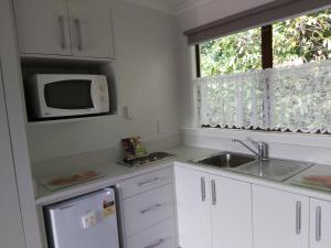 a white kitchen with a sink and a microwave at Matador Motel in Carterton