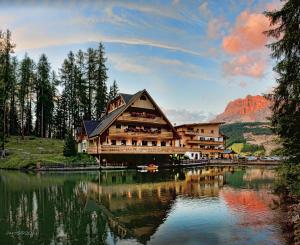 a large wooden building sitting on top of a lake at Residence Ciasa Vedla in Badia