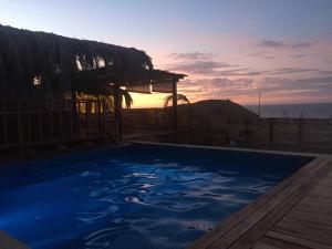 a blue swimming pool with the sunset in the background at Teulu in Máncora