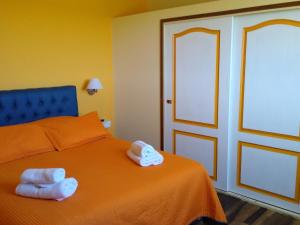 1 dormitorio con 1 cama naranja y 2 toallas en Chacra Arana cabaña de campo, en Villa Regina