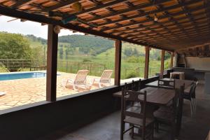 a patio with a table and chairs and a pool at Chacara da Zelma in Capitólio