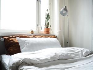 a bed with white sheets and a lamp in a room at 2ndhomes Tampere "Hatanpää" Apartment - Newly Renovated Downtown Apt in a Historic Building in Tampere