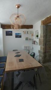 uma sala de jantar com uma mesa de madeira e um lustre em Gîte La Maison Toute de Travers em Le Malzieu-Ville