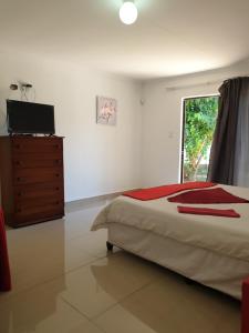 a bedroom with a bed and a dresser and a window at Rose Guesthouse Klerksdorp in Klerksdorp