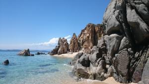 una spiaggia rocciosa con acqua blu e rocce di Ferienapartment At Home Ouranoupolis a Ouranoupoli Altre 42 foto