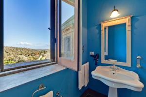 un bagno blu con lavandino e finestra di Borgo del Carato a Solarino