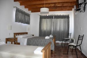 1 dormitorio con 2 camas, mesa y sillas en Apartdora en Yacanto