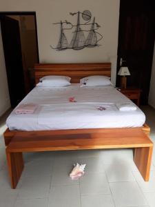 a large bed with a wooden frame with a white mattress at Ti Vanillier in Petit-Bourg