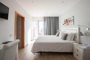 a white bedroom with a bed and a television at Solar de Mos in Lagos