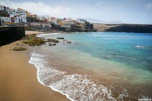 a view of a beach with buildings and the ocean at El retiro azul in Gáldar