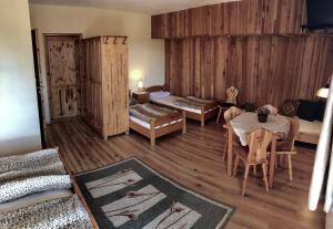 a living room with a table and a room with wooden walls at Apartamenty i pokoje U Marianny in Bukowina Tatrzańska