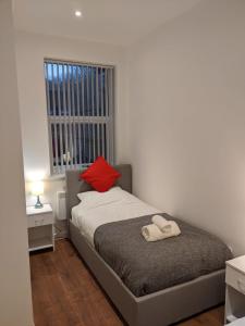 ein Schlafzimmer mit einem Bett mit einem roten Kissen in der Unterkunft Modern Newgate Apartments - Convenient Location, Close to All Local Amenities in Stoke on Trent