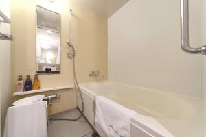 a bathroom with a tub and a toilet and a sink at Meitetsu Inn Hamamatsucho in Tokyo