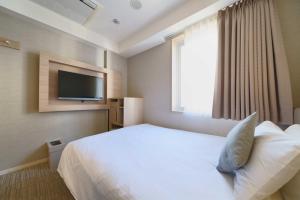 a hotel room with a bed and a television at Meitetsu Inn Hamamatsucho in Tokyo