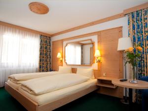a bedroom with a large bed and a mirror at Hotel Ambiente in Saas-Fee