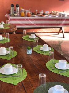 un tavolo in legno con piatti e bicchieri verdi di Pousada In Bali - Maresias a Maresias