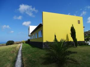 una casa amarilla en una colina con una palmera en Four Winds House, en Altares