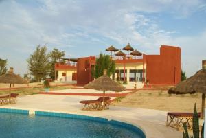 a resort with a swimming pool with chairs and umbrellas at Hotel Gandiol - Commune de Ndiebene- gandiol, Saint louis in Saint-Louis