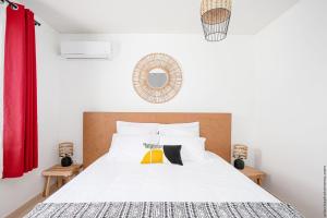 Ducos的住宿－Appart Hotel Martinique - Mellow Yellow，卧室配有白色的床和红色窗帘