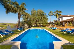 una piscina en un patio con sillas y una casa en La Granja de Antonio en Alhaurín el Grande