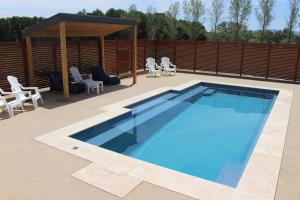 a swimming pool with chairs and a gazebo at 3 WISE MONKEYS, MANSFIELD in Mansfield