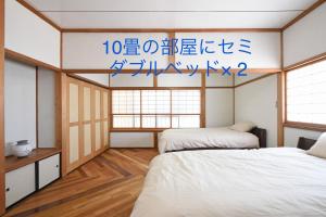 一棟貸し切り ゲストハウス Sai في Yasugi: سريرين في غرفة مع كتابة على الحائط