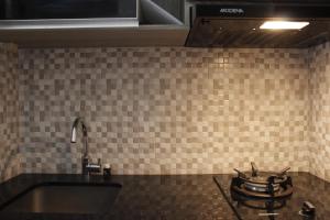 a tiled kitchen with a sink and a stove at Elegant 2BR Gateway Pasteur Apartment near Exit Toll Pasteur By Travelio in Bandung