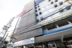 a tall white building with a sign in front of it at A Capsule Hostel in Manila