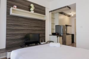 タンゲランにあるFully Parquette City View Studio Apartment at M-Town Residence By Travelioの大きな白いベッドとテレビのある寝室