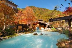 a river in front of a building with a bridge at Awanoyu in Matsumoto