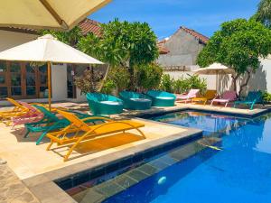 ein Swimmingpool mit Liegestühlen und Sonnenschirm in der Unterkunft Tír na nÓg Beachfront Resort in Gili Trawangan