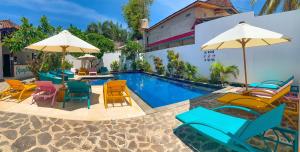 a group of chairs and tables next to a swimming pool at Tír na nÓg Beachfront Resort in Gili Trawangan