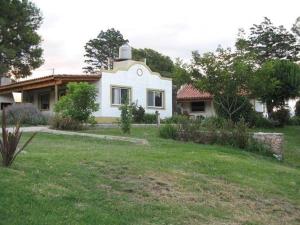 una casa blanca con un patio de hierba delante de ella en La Candelaria - Casas de Campo - en Sierra de la Ventana