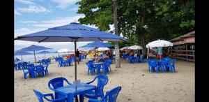 grupa niebieskich krzeseł i parasoli na plaży w obiekcie Angra dos Reis Casa a 150 metros da Praia Mambucaba na Vila Histórica divisa com Paraty w mieście Angra dos Reis